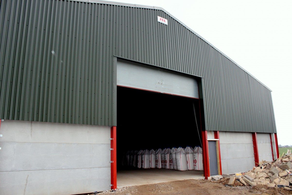 Corn store with juniper green plastisol cladding and roller shutter door