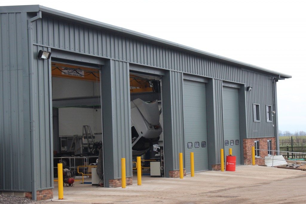 Grey clad commercial steel-framed workshop building with roller shutter doors